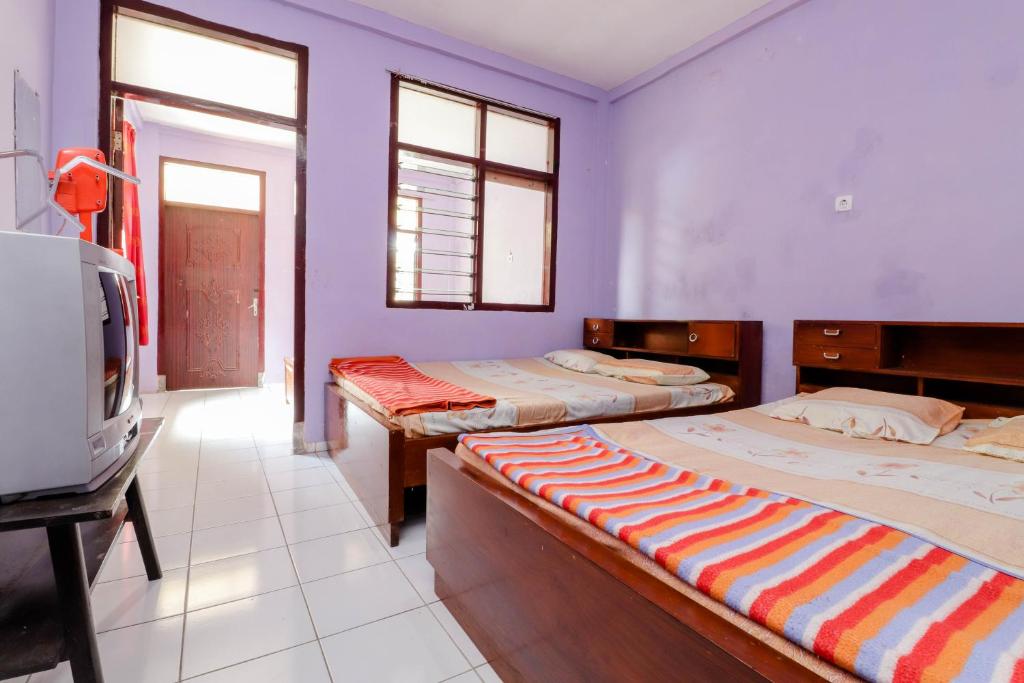 马格朗Penginapan Sedyo Rahayu的紫色墙壁和窗户的客房内的两张床