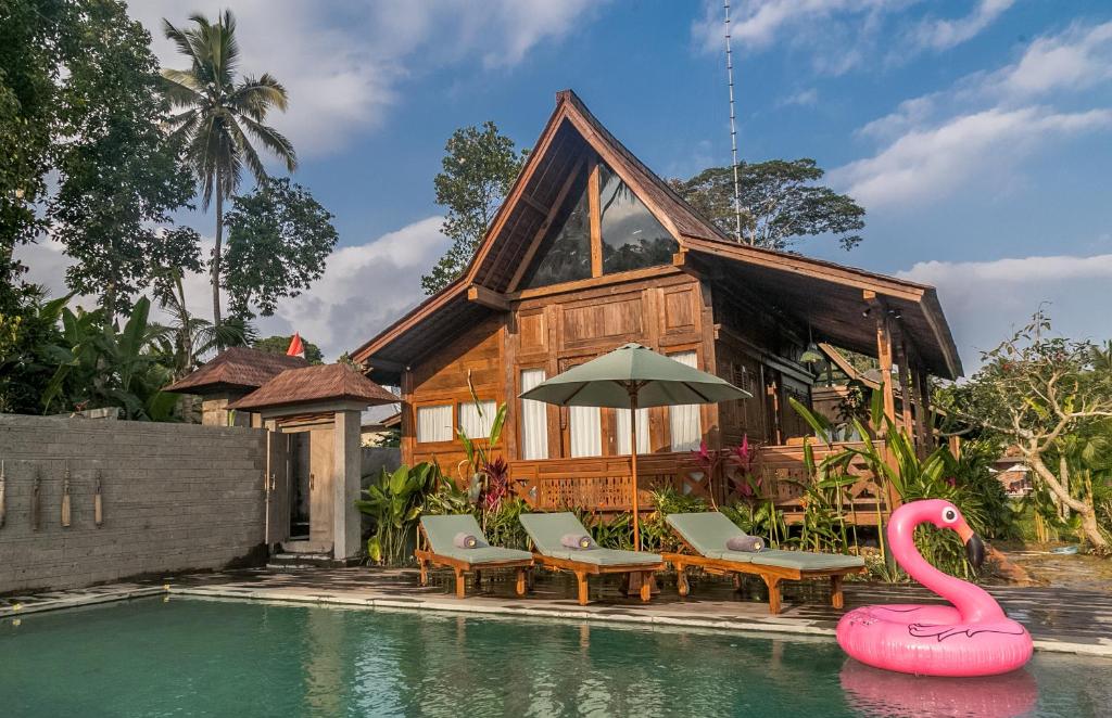 乌布Benisari Batik Garden Cottage的一座带游泳池和粉红色火烈鸟的房子