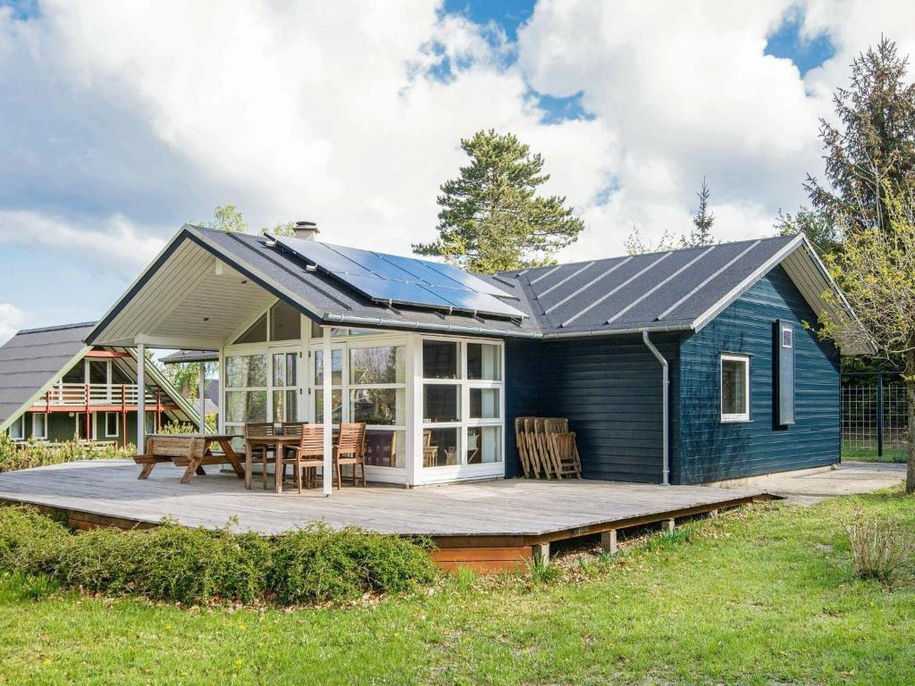 格莱斯堡6 person holiday home in Glesborg的蓝色房子,甲板上设有太阳能屋顶