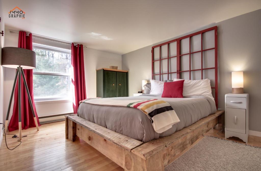 Saint-Jean-des PilesMaison Cadorette的一间卧室配有一张带红色窗帘的木床