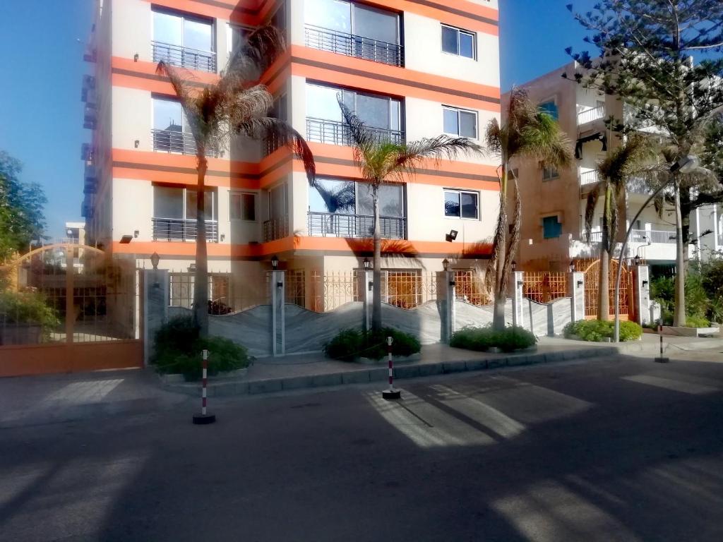 亚历山大Al Raya Apartments的一座高大的建筑,前面有棕榈树