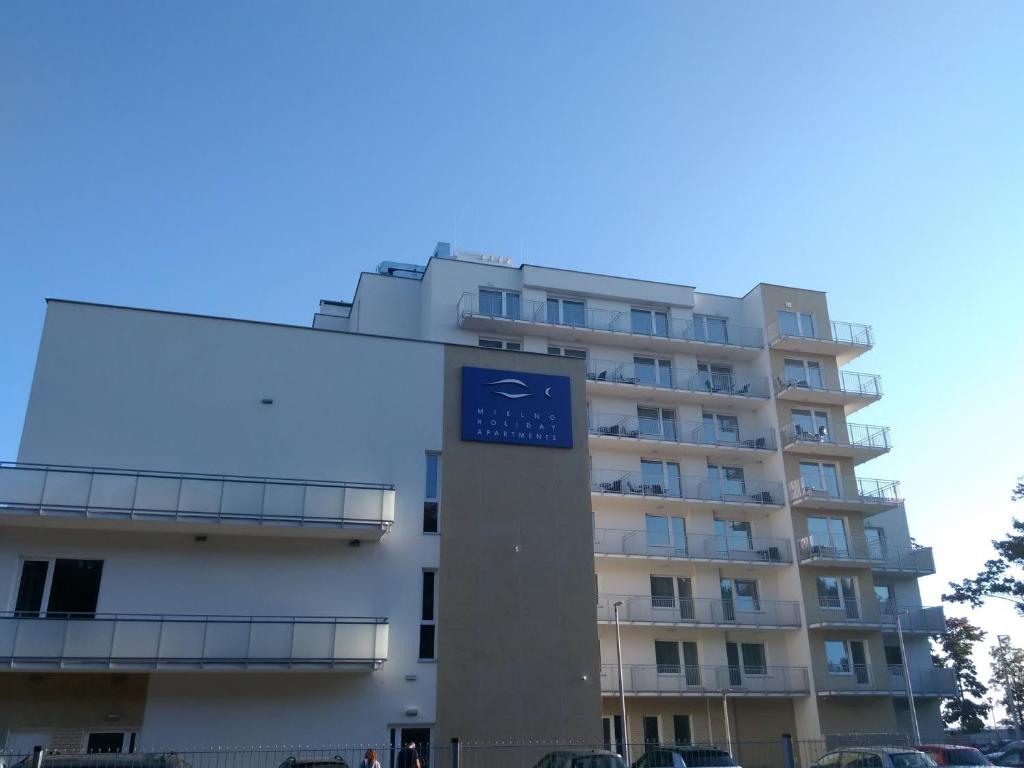梅尔诺Mielno Holiday Apartament 401 typu studio的一座高大的公寓楼,上面有蓝色的标志