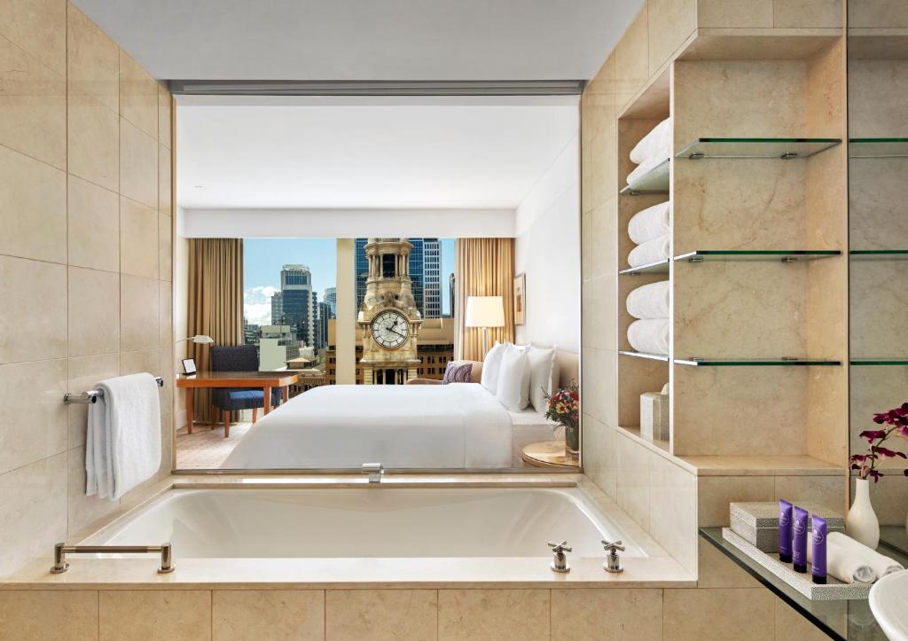 悉尼The Fullerton Hotel Sydney的一间带床和大镜子的大浴室