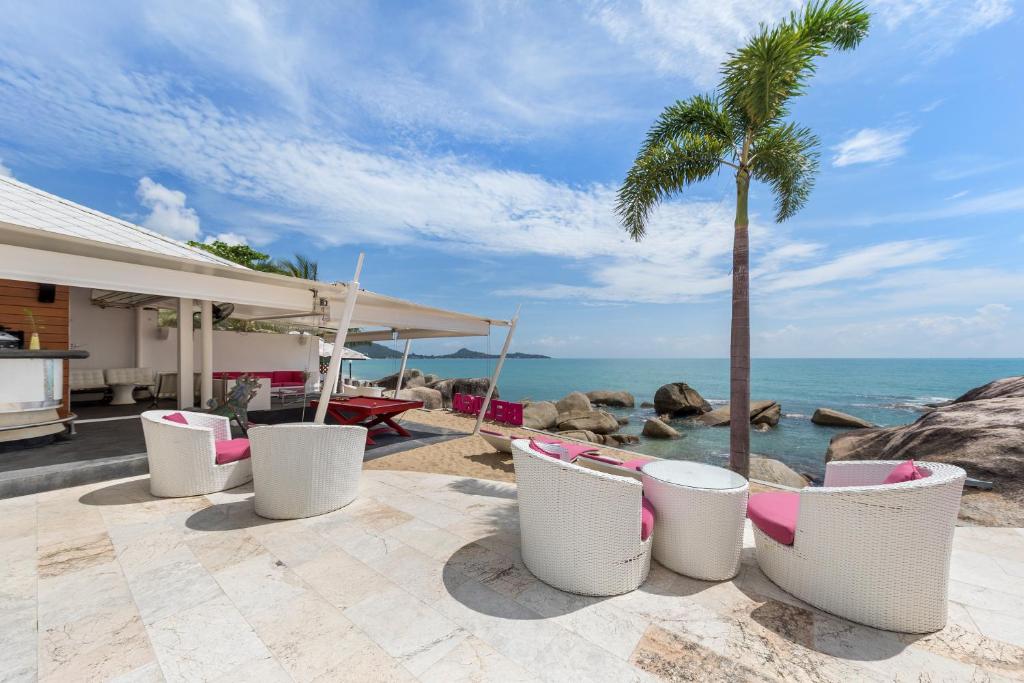 拉迈白鲸精品酒店的一个带椅子和棕榈树的庭院和大海