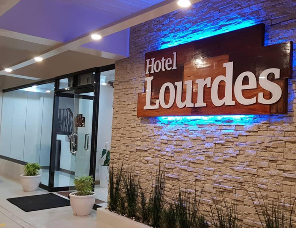 拉瓦格Hotel Lourdes的酒店大堂的砖墙上标有标志