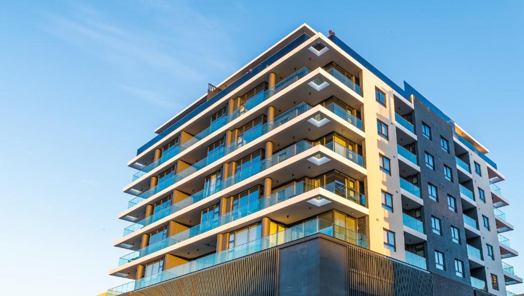 开普敦Latitude Aparthotel by Totalstay的一座高大的公寓楼,后面有蓝色的天空