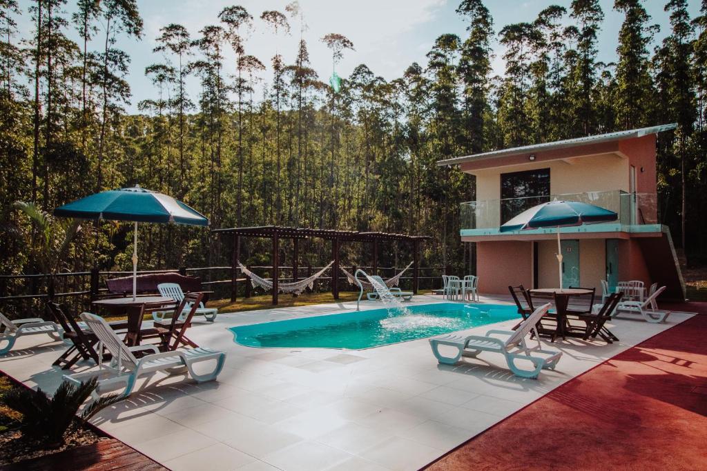 Mauá da SerraRECANTO DA SERRA的庭院设有游泳池、椅子、桌子和遮阳伞。