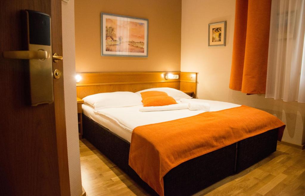松博特海伊Hotel Wagner的一间卧室配有一张带橙色毯子的床