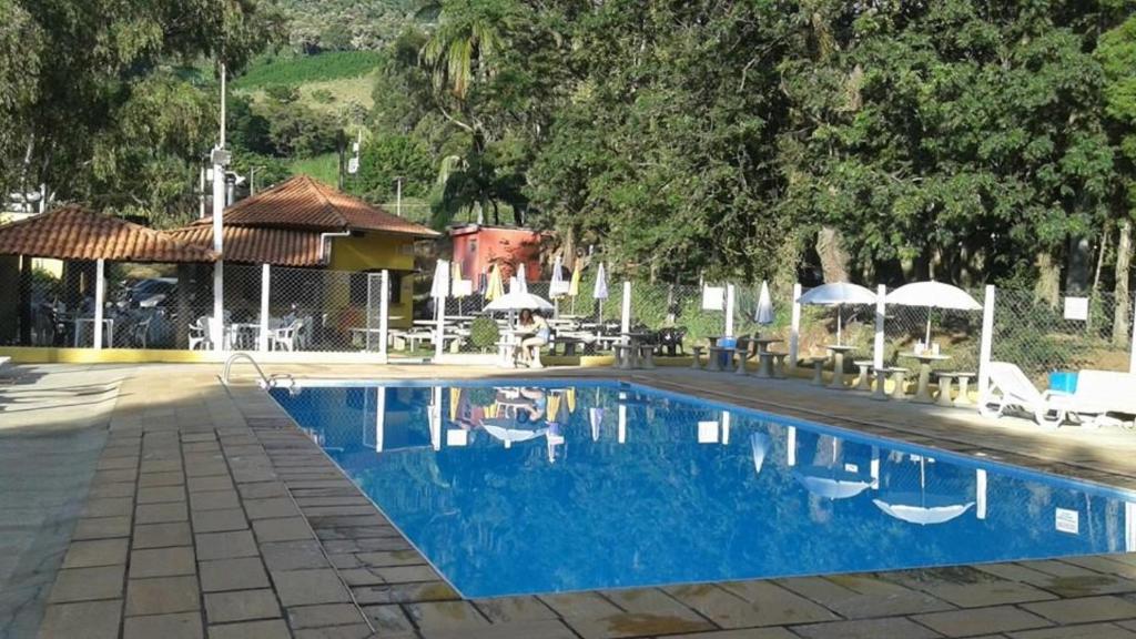 阿瓜斯达普拉塔Camping e Pousada Paiol的毗邻带椅子和遮阳伞的蓝色游泳池