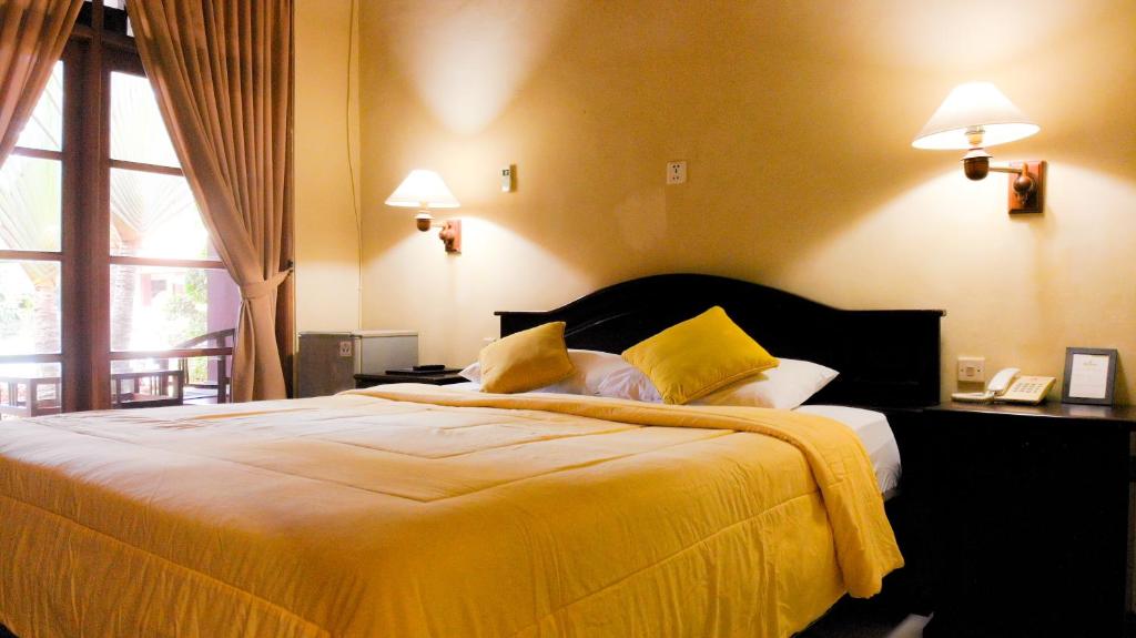 库塔Masainn Hotel Kuta的一间卧室配有一张带黄色床单的大床