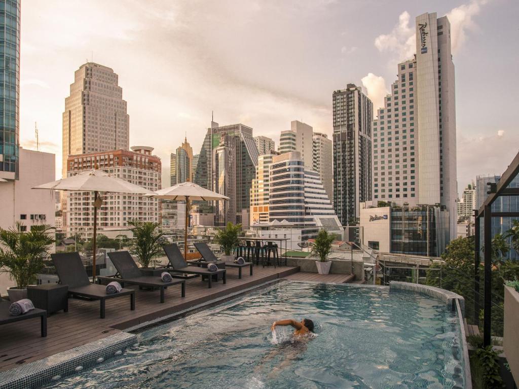 曼谷Tastoria Collection Sukhumvit - SHA Extra Plus的城市天际线顶端的游泳池游泳的人