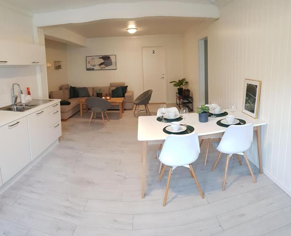翁达尔斯内斯I hjerte av Åndalsnes sentrum的厨房以及带白色桌椅的起居室。