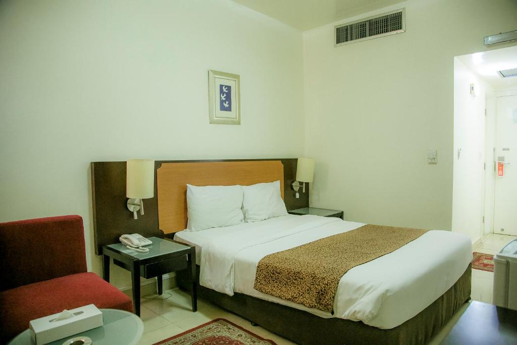 迪拜Phoenicia Grand Hotel的酒店客房,配有一张床和一张红色椅子