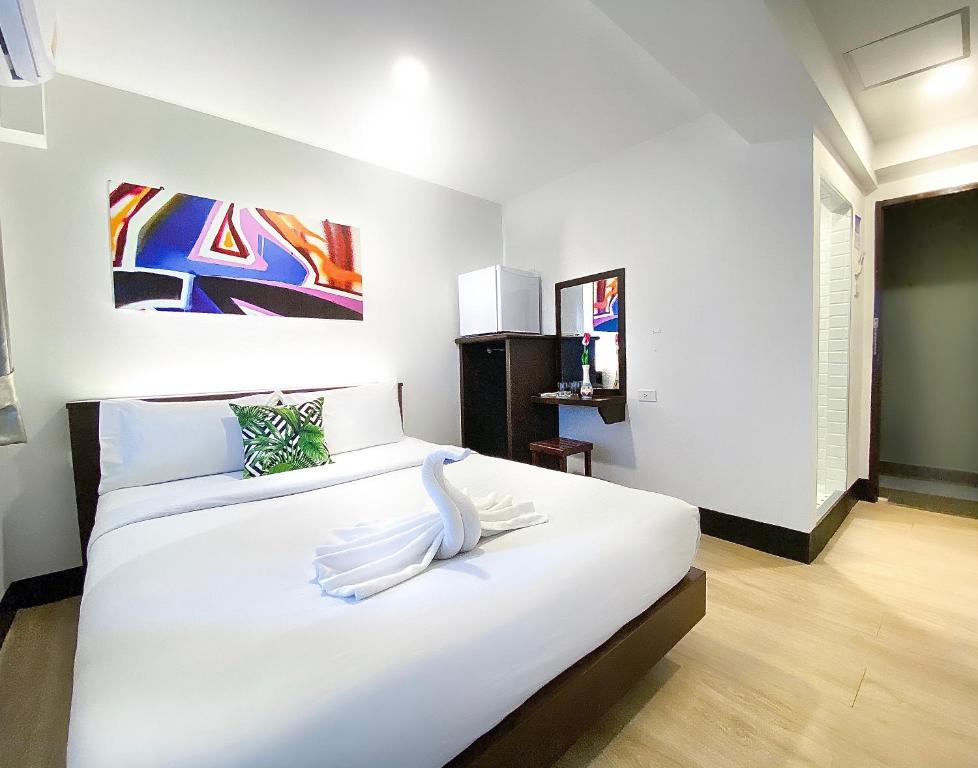 芭堤雅市中心新星旅馆的卧室配有一张白色大床和天鹅