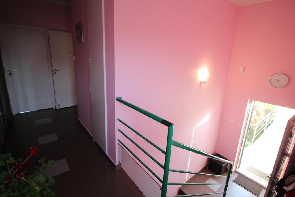 RamučiaiDangus的一间设有粉红色墙壁的客房,配有楼梯和时钟