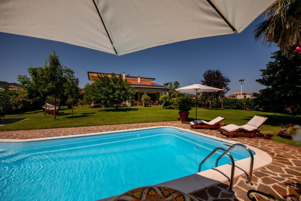 马帝斯兹罗Villa Tigli Luxury B&B的一座房子旁带遮阳伞的游泳池