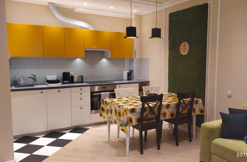 德鲁斯基宁凯Full House Apartments的厨房配有桌椅和黄色橱柜