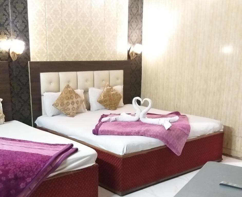 阿姆利则Hotel Shehnaz Inn - Walking Distance for Golden Temple的一间卧室配有两张紫色和白色床单