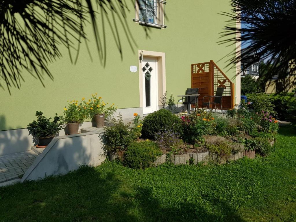 萨克森自由州诺伊斯塔滕Ferienwohnung Karlguth的绿色的房子,庭院里设有植物庭院