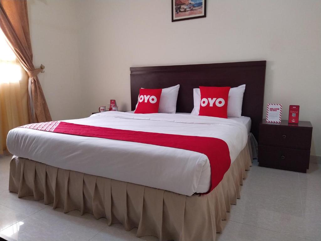 ShāhiqSuper OYO 107 Al Areen Hotel Apartments的一间卧室配有一张带红色枕头的大床