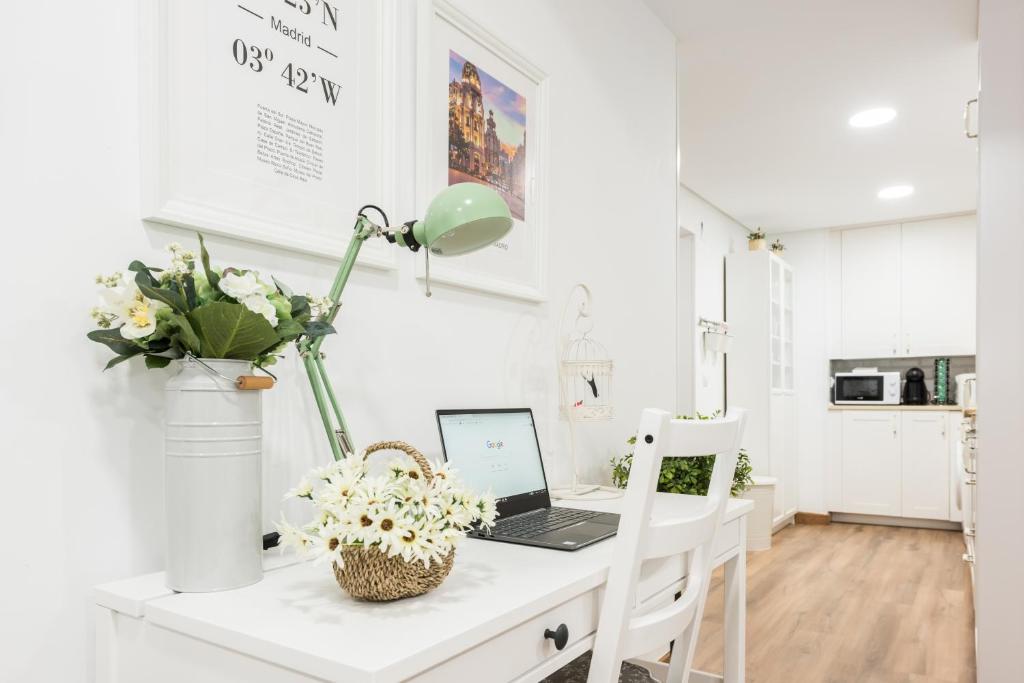 马德里Apartment Sol Gran Vía的白色的厨房,配有一张桌子和一台笔记本电脑