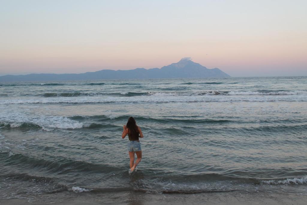萨尔蒂Magdalena & Bambino apartments的一位在海滩上水中行走的女人