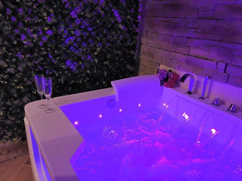 圣玛格丽塔-利古雷Historia Vitiello: The First Experience Suite的紫色浴缸,配有葡萄酒和葡萄酒杯
