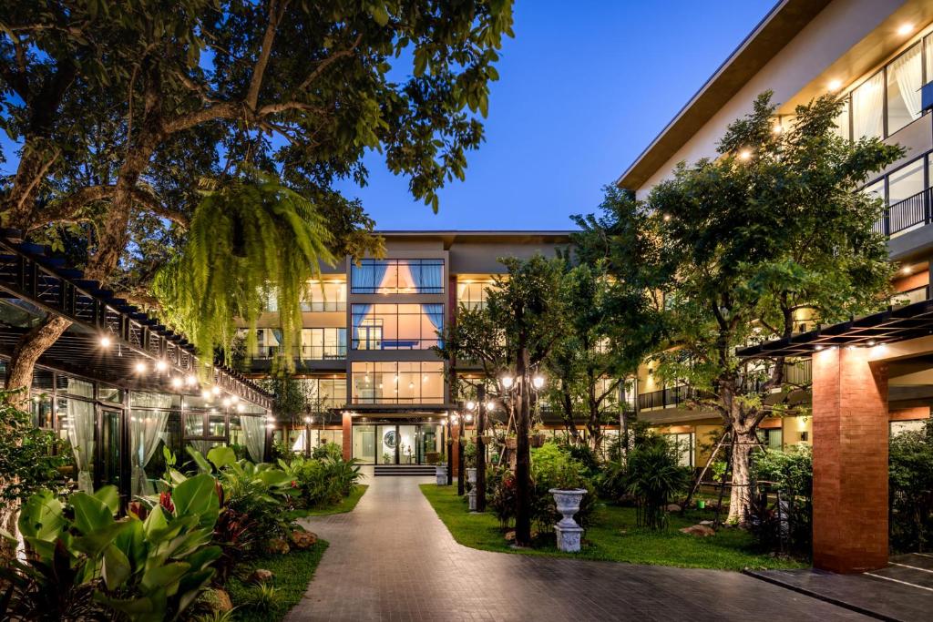 武里南T-REX BURIRAM BOUTIQUE HOTEL New Hotel in Buriram的享有树木和灯光的建筑外部景色