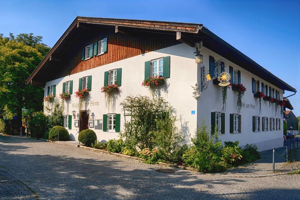 施塔弗尔湖畔塞豪森Gasthof zum Stern的白色的建筑,上面有绿色百叶窗和鲜花