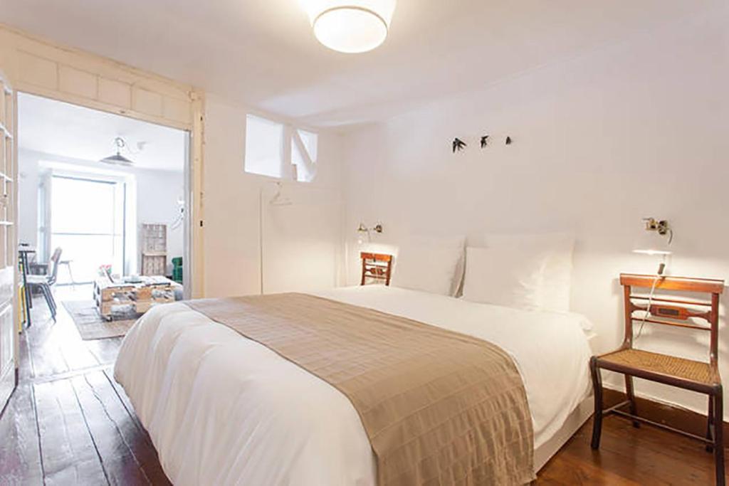 里斯本巴洛奥尔多橡树谷公寓的卧室配有一张白色大床和一把椅子