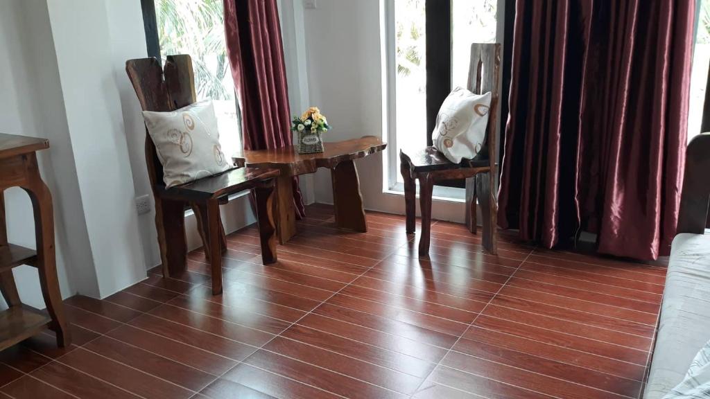 长滩岛Marnin's Place的客房铺有木地板,配有椅子和窗户。