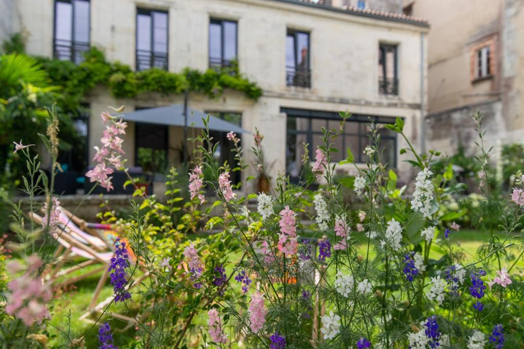 拉罗谢尔Escale Rochelaise, gîte urbain avec SPA bain nordique et sauna tonneau的一座花园,在一座建筑前种有鲜花
