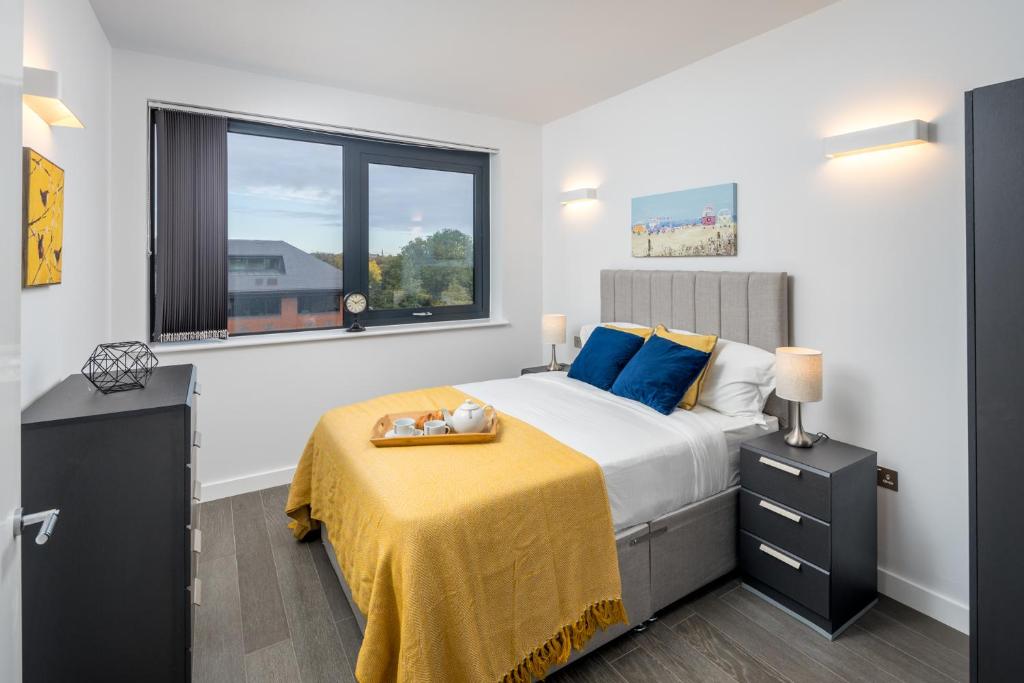 圣奥尔本斯St Albans City Apartments - Near Luton Airport and Harry Potter World的一间卧室配有一张带黄色毯子和窗户的床