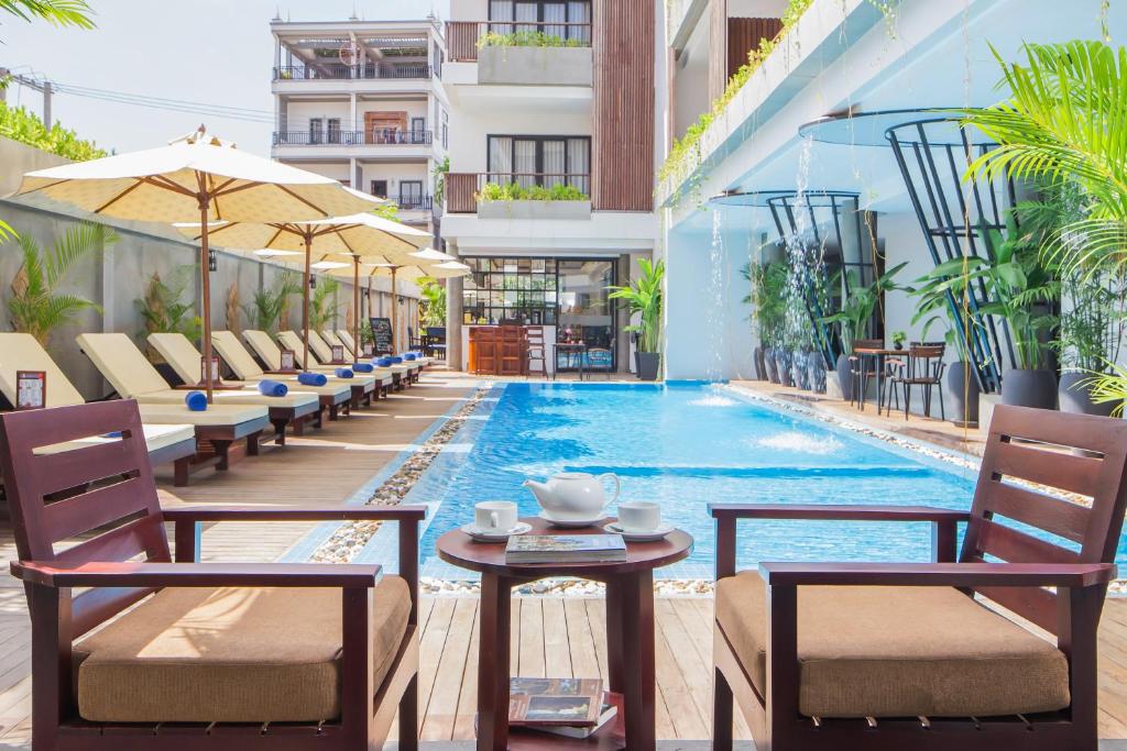 暹粒Siem Reap Palace Hotel & Spa的一个带游泳池、椅子和桌子的酒店