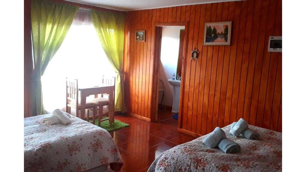 科伊艾科Apart Hotel Arrayán的一间卧室设有两张床、一把椅子和一个窗户。