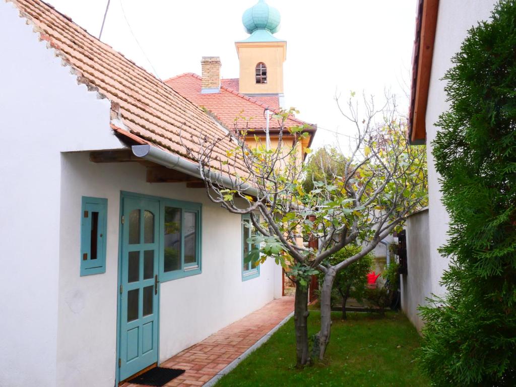 佩奇Tettyei Házikó的白色的房子,有绿门和一棵树