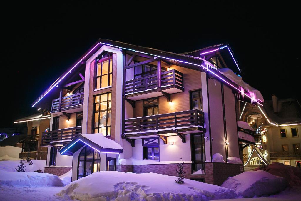 什瑞哥什阿尔卑斯俱乐部公寓式酒店的雪中紫色灯的房子