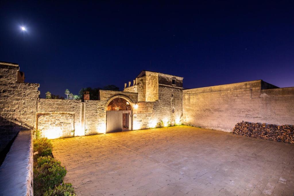 鲁法诺Masseria Violante Boutique Hotel的石头建筑,晚上有庭院