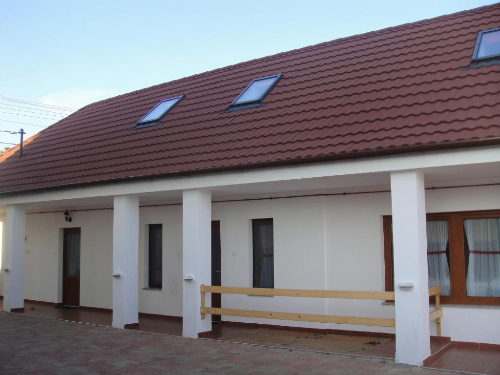保克什Paks Panzió的白色的建筑,有棕色的屋顶和长凳