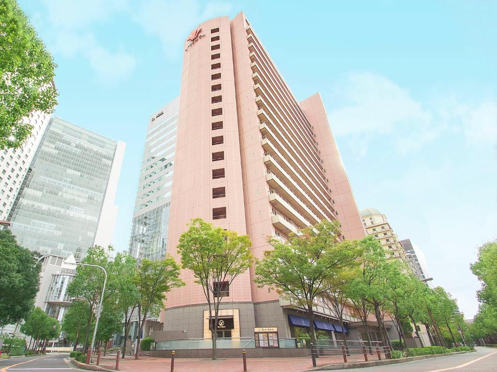 大阪西梅田哈顿酒店的一座高大的粉红色建筑,前面有树木