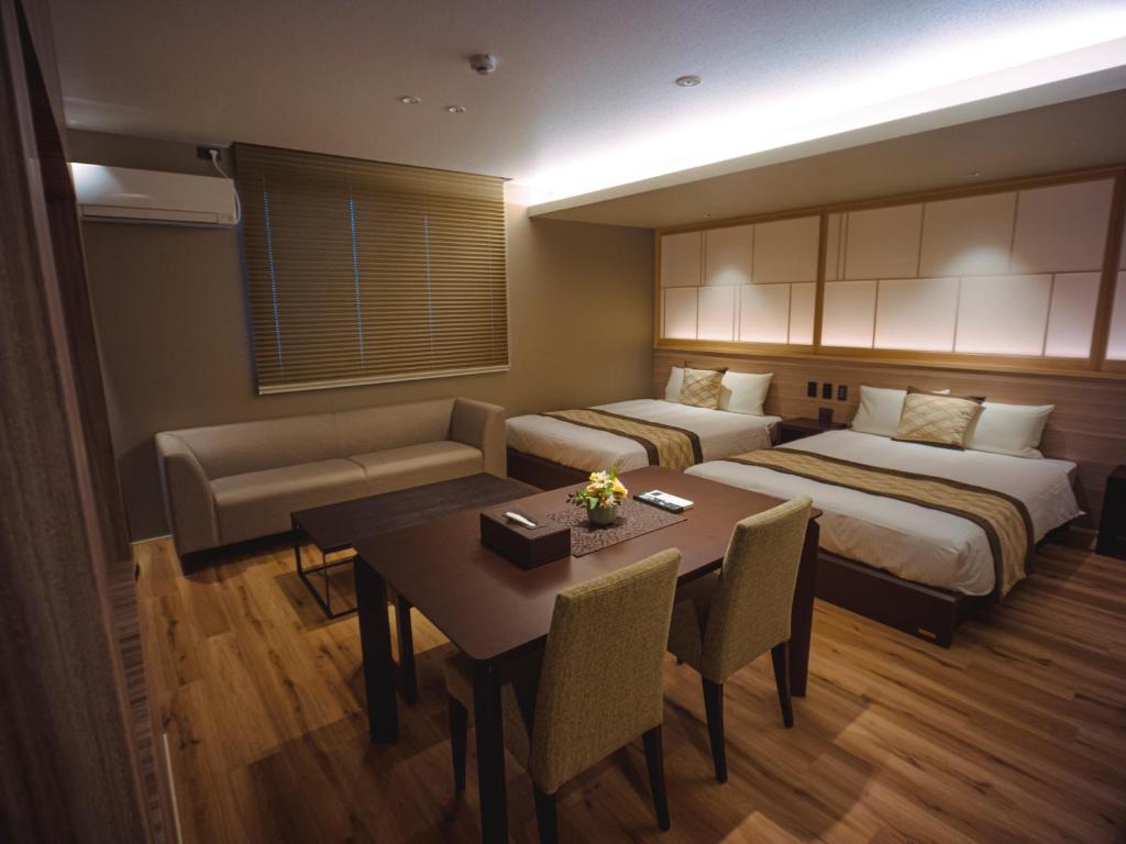 别府GRAND BASE Beppueki的酒店客房带两张床和一张桌子以及椅子。