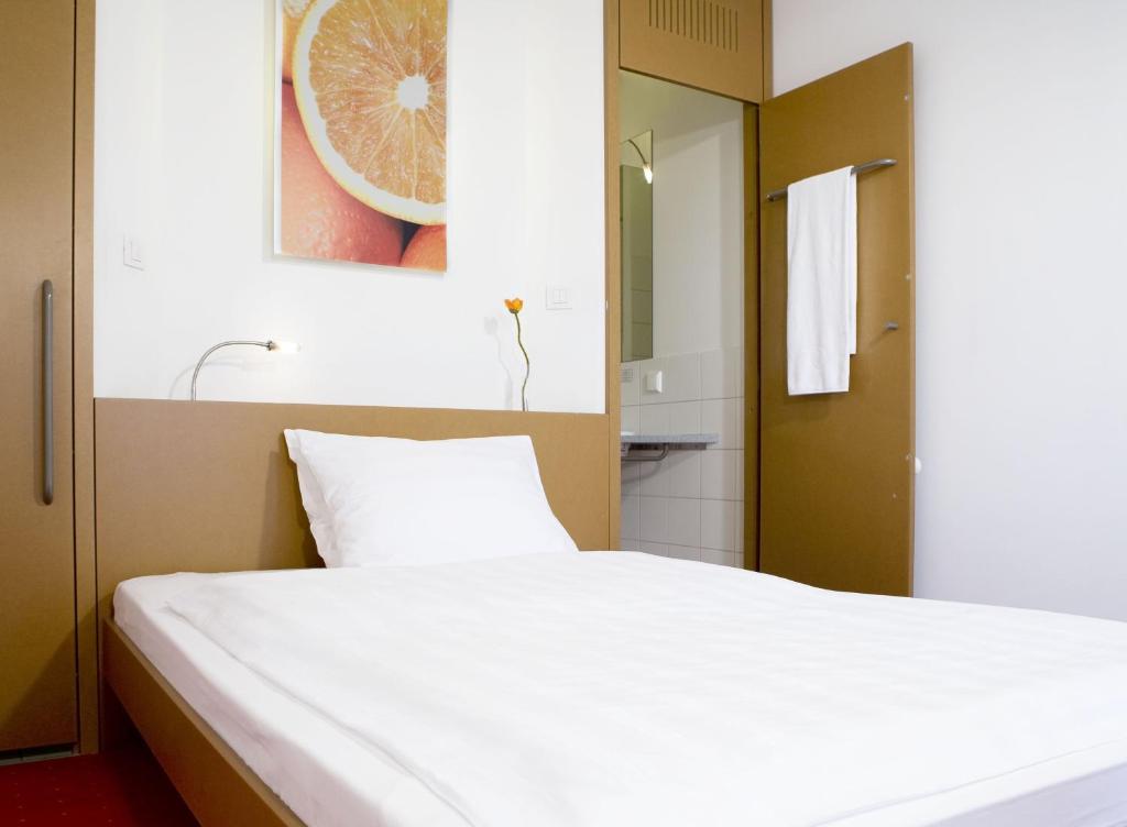 维也纳新城橙色翅膀维也纳新城酒店的一间带白色床的卧室和一间浴室
