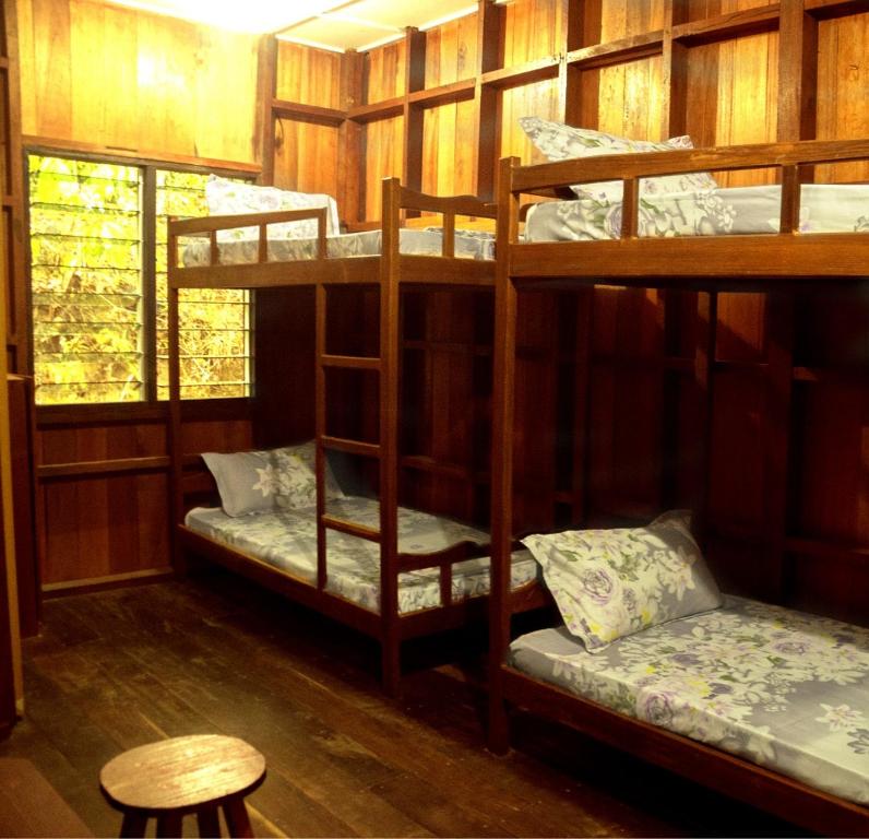 山打根Kinabatangan Wildlife Lodge的配有一张桌子和一张凳子的客房内的两张双层床