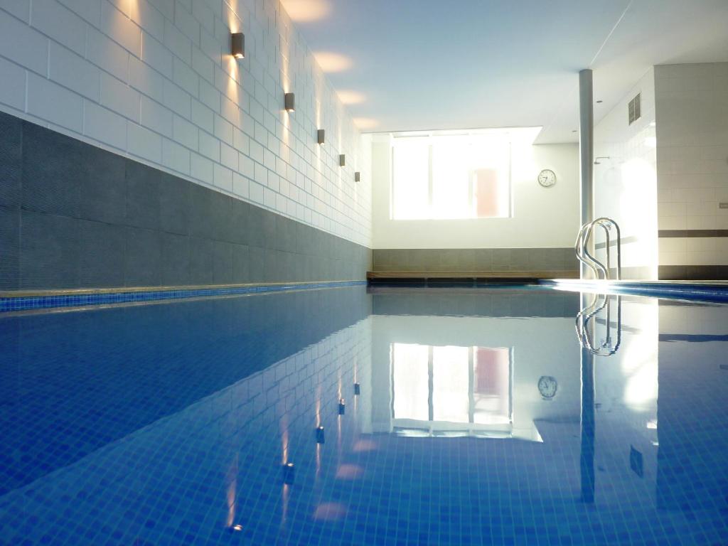 鲁汶英德拉高级健康设施住宿加早餐旅馆的一个带蓝色瓷砖地板的游泳池和一个游泳池