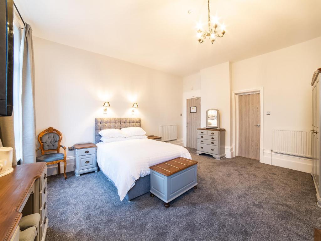 武姆韦尔Churchill's Hotel的卧室配有一张白色大床和一把椅子