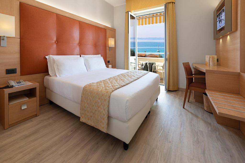 巴多利诺Hotel GARDENIA & Villa CHARME Adults Friendly 10Plus的配有一张床、一张书桌和一扇窗户的酒店客房