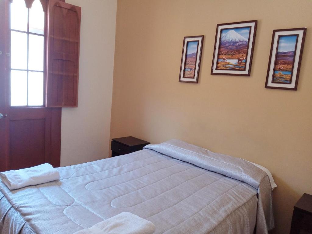 阿雷基帕芒果住宿加早餐旅馆的卧室配有一张床,墙上挂有图片