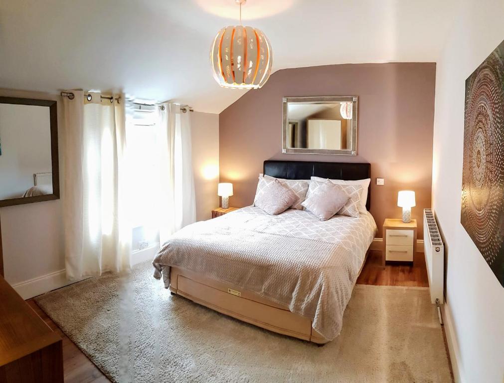 朴次茅斯Cottage Grove Homestay rooms的一间卧室配有一张带镜子和吊灯的床。
