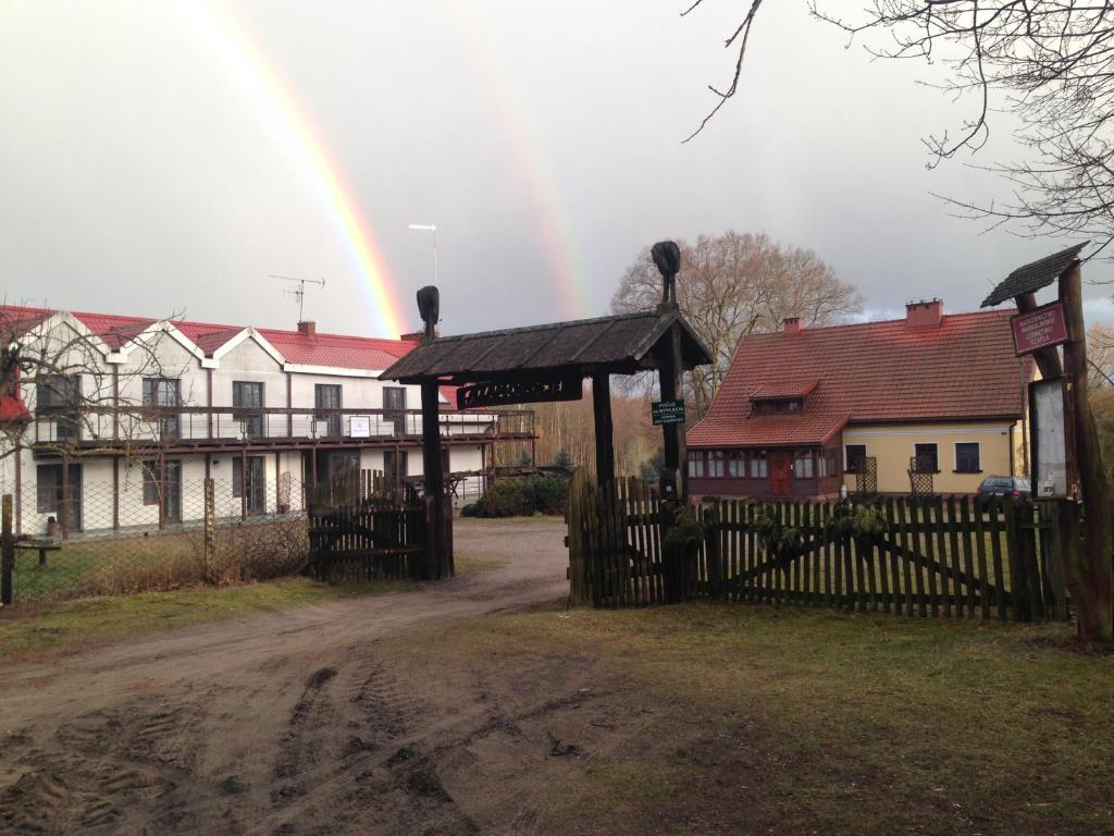 ZamordejeLeśniczówka nad jeziorem的彩虹在一座带门和栅栏的房子上