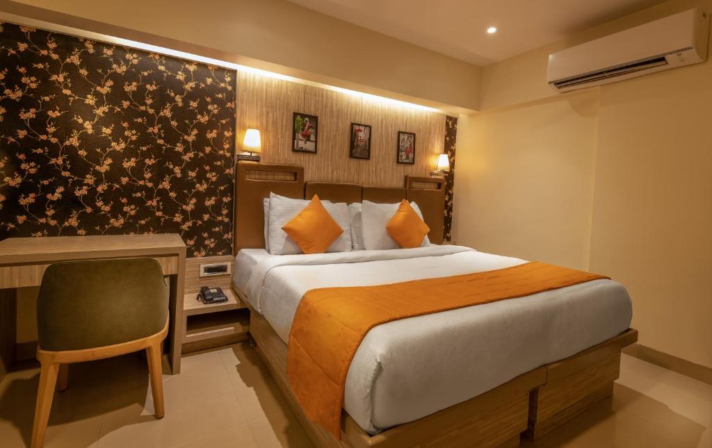 孟买孟买国际机场东方紫菀酒店的一间卧室配有一张床和一张桌子及椅子